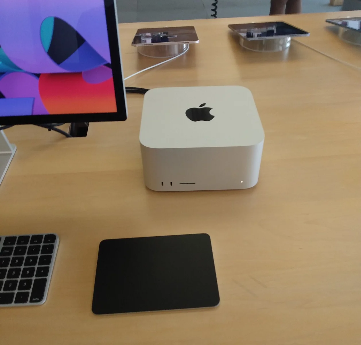 매장 테이블 위에 놓인 Apple의 Mac Studio 데스크톱 본체와 Studio Display 모니터, Magic Keyboard, Magic Trackpad가 함께 배치된 모습
